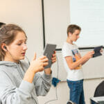 Zwei Teenager, ein Junge und ein Mädchen, halten je ein iPad und erforschen damit die Augmented Reality.